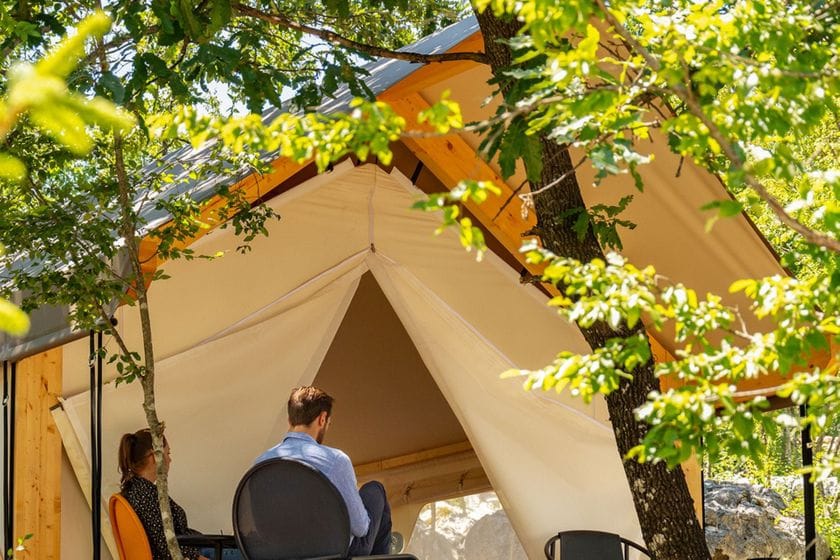 Glampingo palapine ir žmonės šalia jos